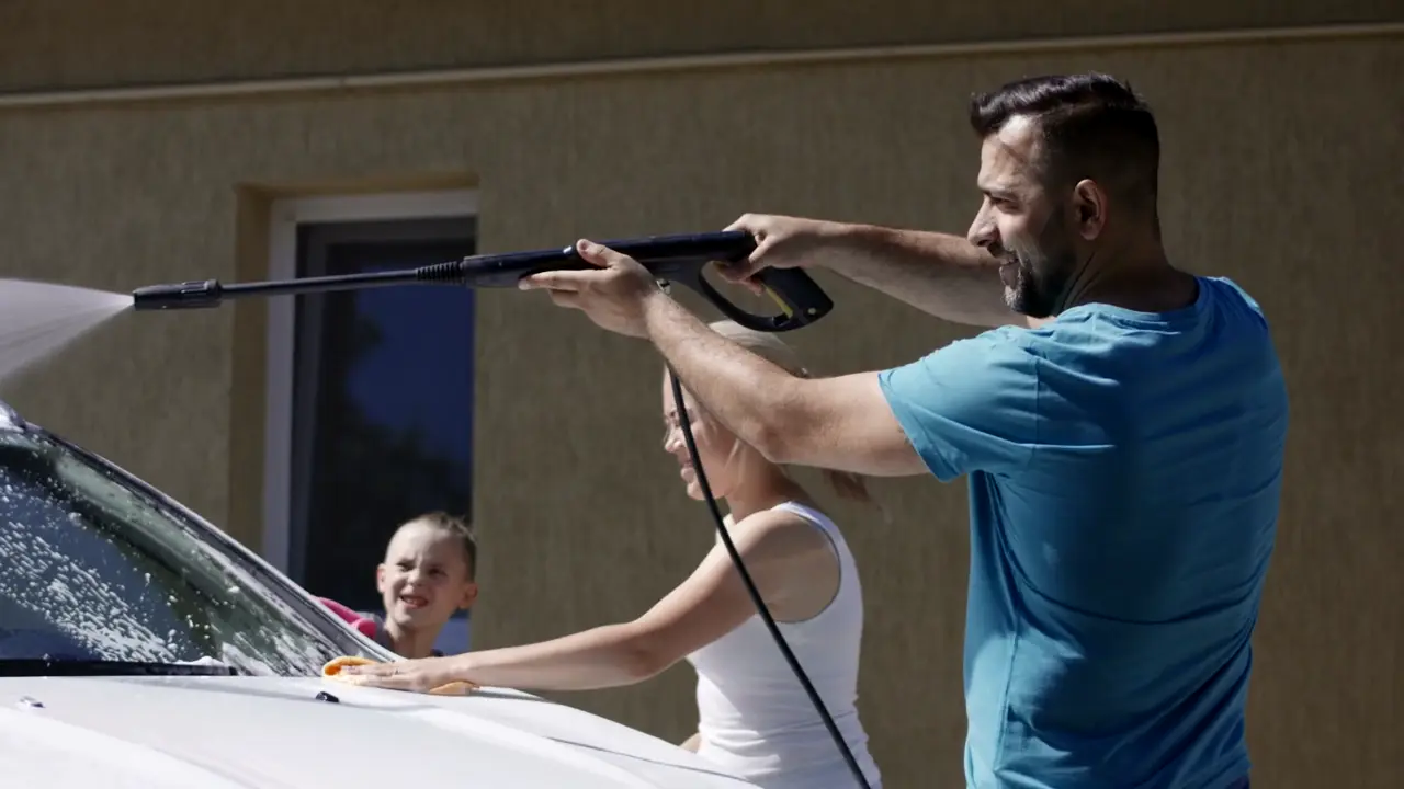 Father and daughter washing the family car in their driveway